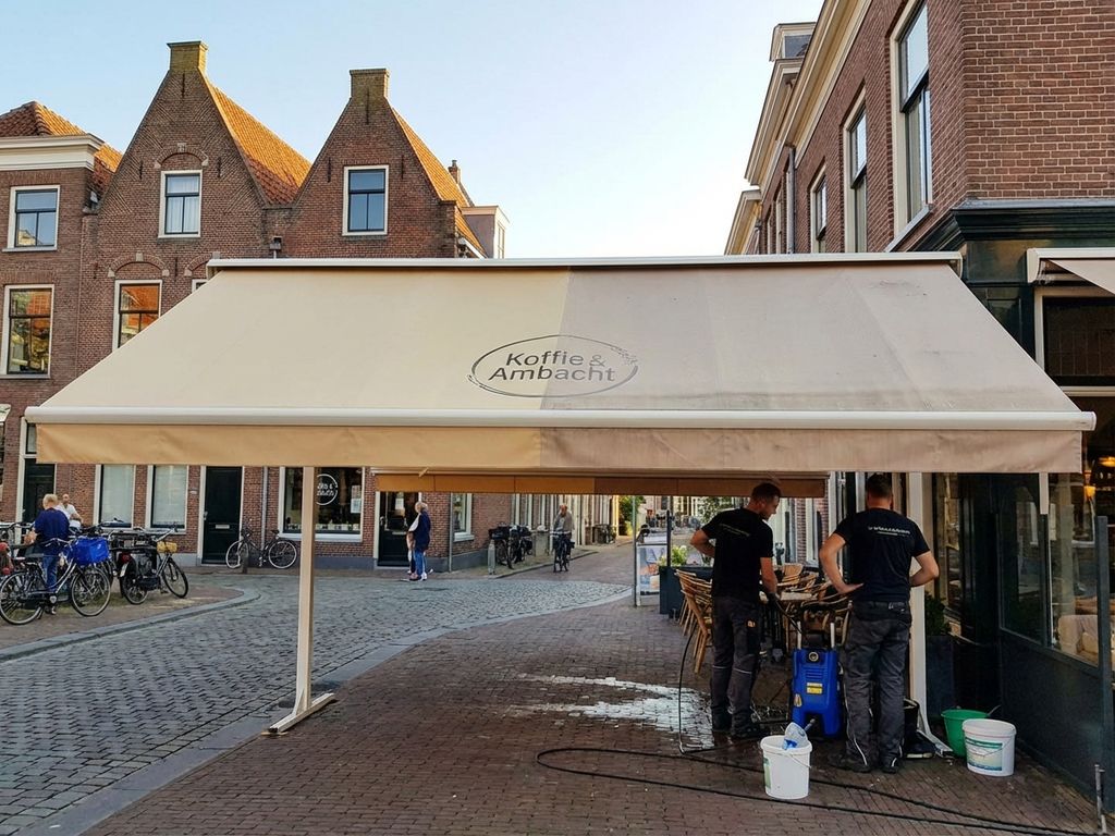 Schone commerciële luifel boven Nederlands café terras toont verschil tussen gereinigd en verweerd gedeelte