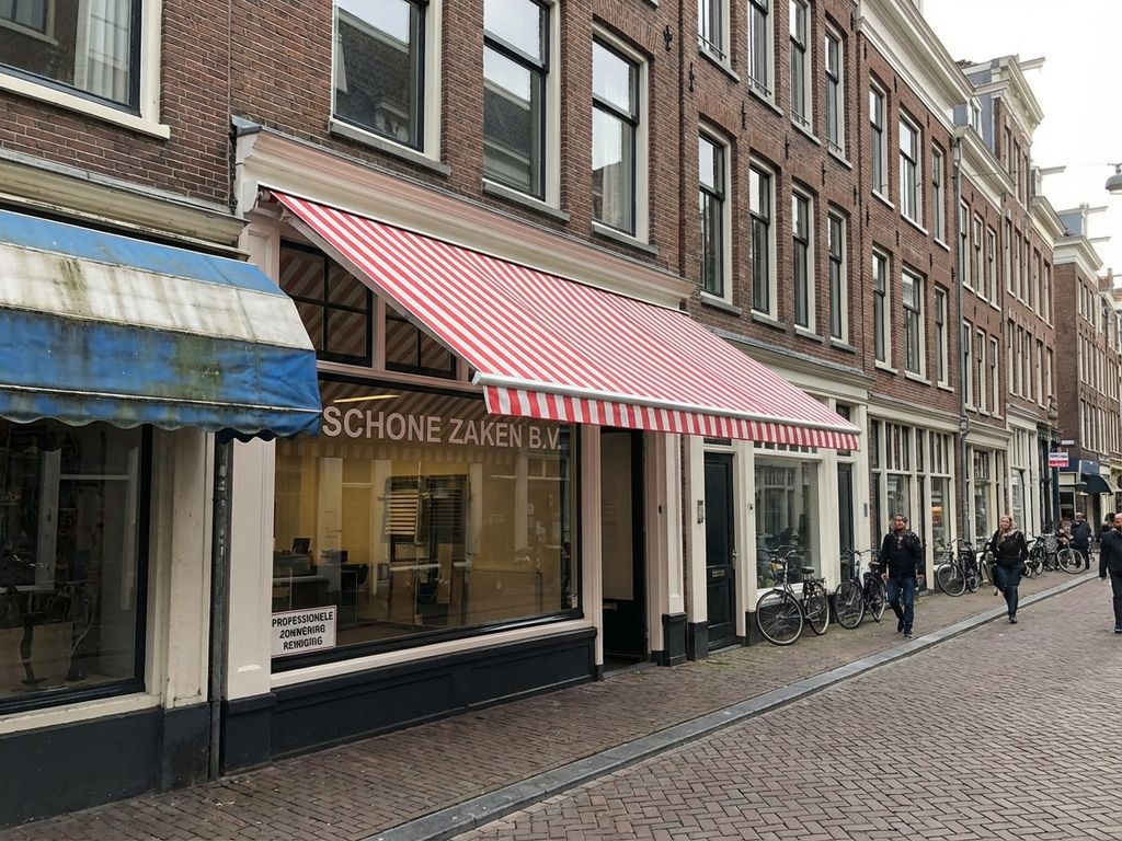 Schone rood-witte luifel van Nederlandse winkel na professionele reiniging, contrast met verweerde buurluifel