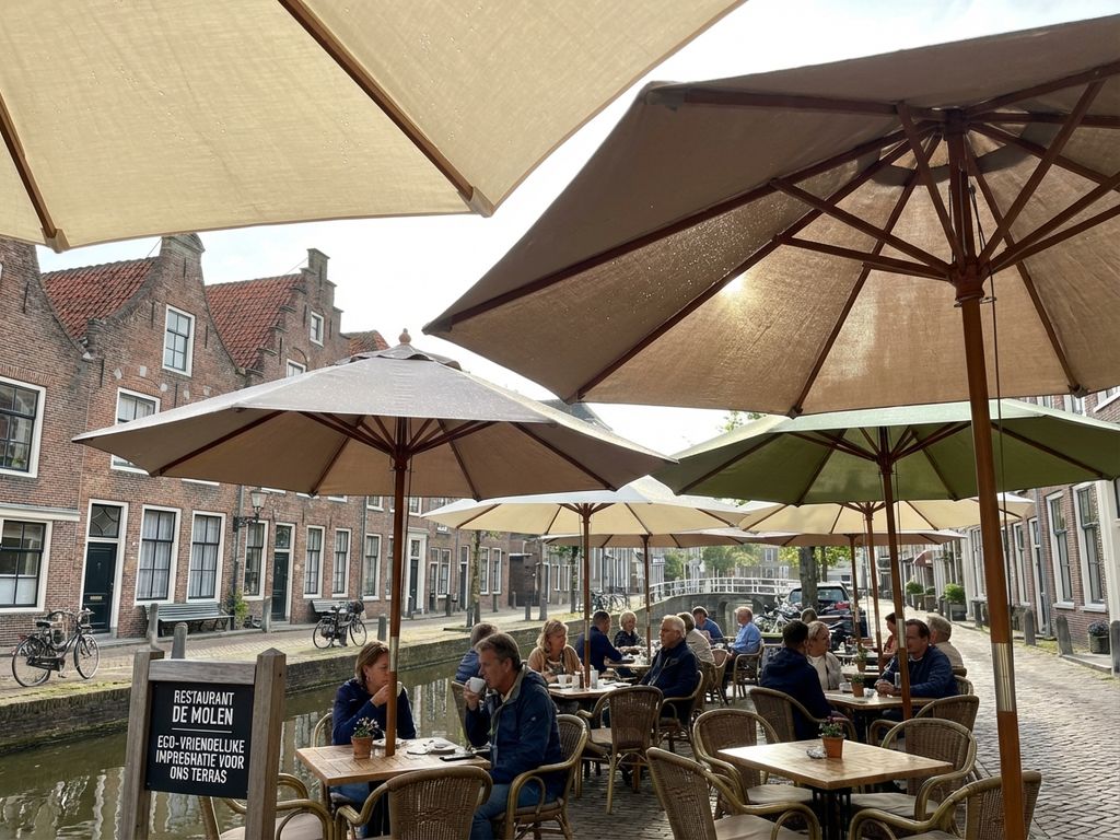 Terras van Nederlands restaurant met behandelde parasols langs gracht, ochtendlicht toont waterdruppels op duurzame coating