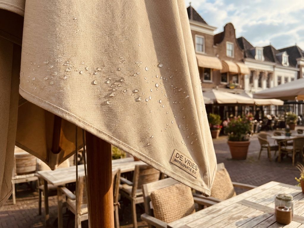 Parasol doek met waterdruppels op restaurant terras toont waterafstotende behandeling en onderhoud kwaliteit