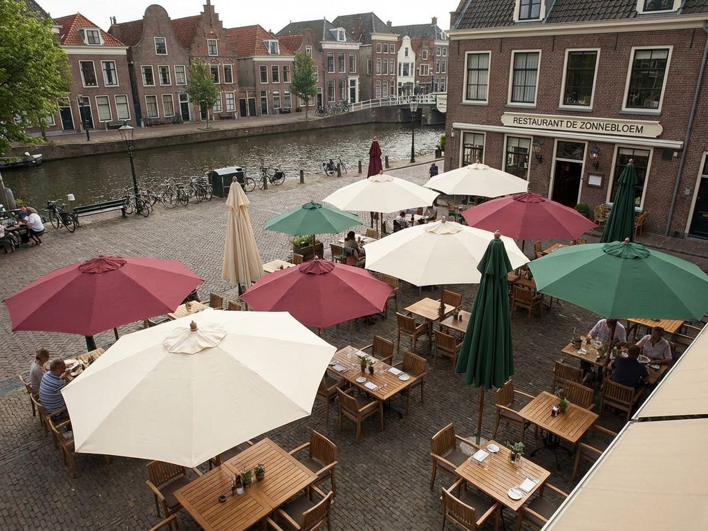 Schone parasols in crème, bordeaux en groen op restaurant terras met Nederlandse grachtenarchitectuur op achtergrond