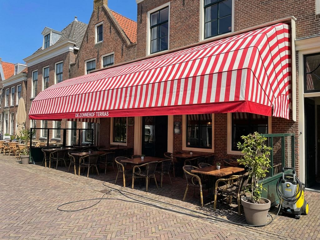 Schoon gestreept zonnescherm boven terras met houten tafels en stoelen, professionele schoonmaakdienst Nederland