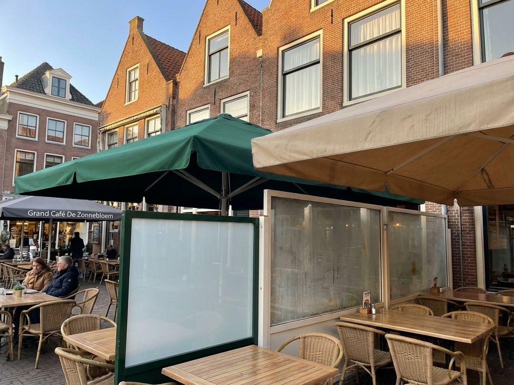 Nederlands restaurantterras met buitenschermen en zonwering in verschillende onderhoudstoestanden bij bakstenen gebouwen