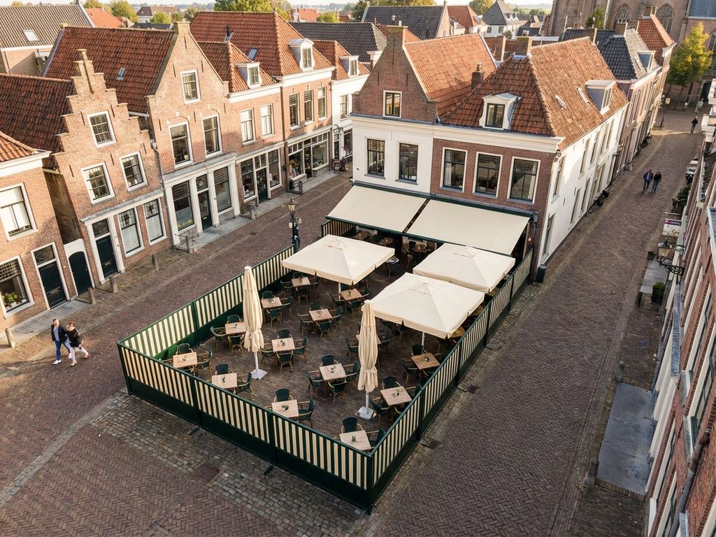 Luchtfoto van schoon restaurant terras met terrasschermen en parasols tussen Nederlandse bakstenen gebouwen