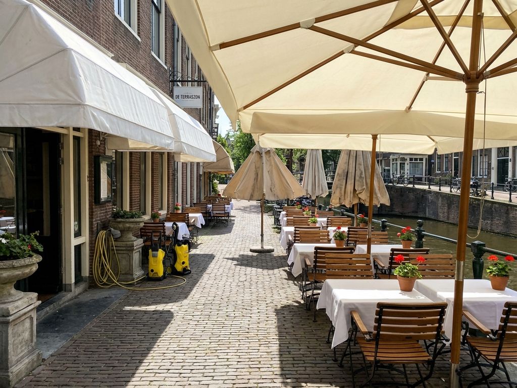 Schoon restaurantterras met witte zonwering en parasols die schaduw werpen over lege tafels in Nederlandse setting