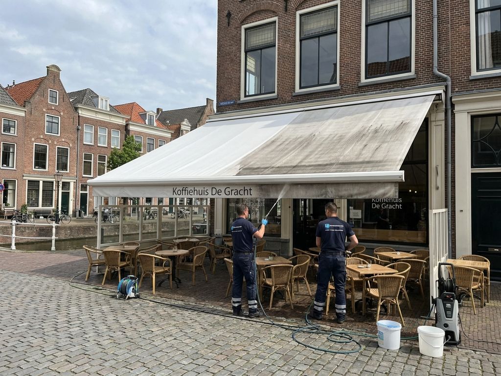Professionele reiniging van wit zonnescherm op Nederlands café terras met traditionele bakstenen architectuur