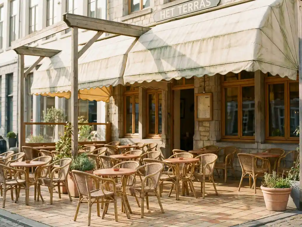 Houten luifel met licht verweerd doek boven een zonnig terras van een Nederlands restaurant met stoelen en kleine tafeltjes.