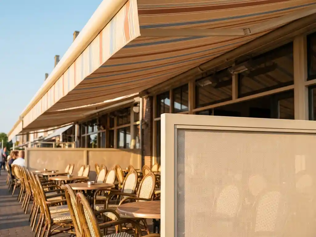 Beige terrasschermen op zonnig Nederlands restaurantterras met canvas luifel, bistrostoelen en ronde tafels in warm middaglicht.